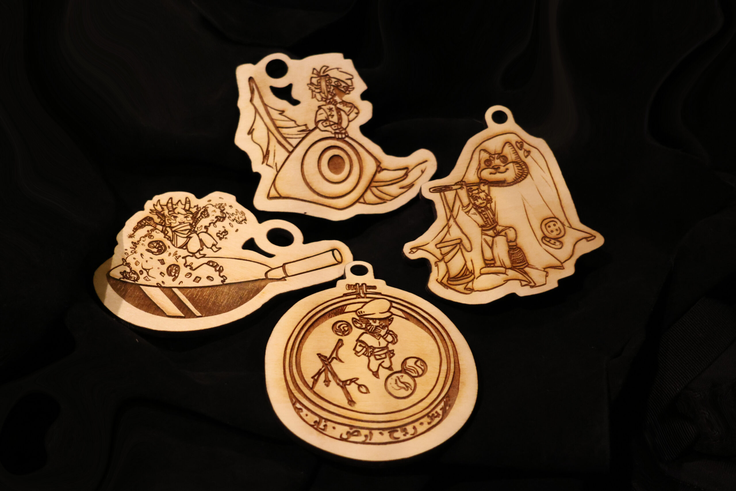 Four double-sided ornaments depicting characters from a tabletop role play game we called "The Mysteries".
The leftmost character is a small goblinoid with a pair of horns being tossed in a wok with shrimp fried rice. This is Wade.
Topmost first and foremost has a large feather behind and eye. Behind the eye a figure. This is Ixis. They are mostly obscured with one eye visible and their finger held to their lips hiding a maniacel grin.
Rightmost is a small figure sewing a dog embrodery onto a hankerchief. The figure is about as tall as his embrodery needle. This is Luc, a man with tusk like lower canines and small horns.
Bottom is Iskra the jin. He wears a large hat that obscures his face. He seems to be thinking as he stands inside his arcane focus of a embrodery hoop with arcane symbols carved in the sides. Surrounding Iskra is some marbles and sticks.